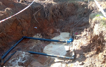 Zdjęcie przedstawia odkryty wykop ziemny, w którym widoczne są czarne rury, połączone niebieskim złączem zaciskowym.